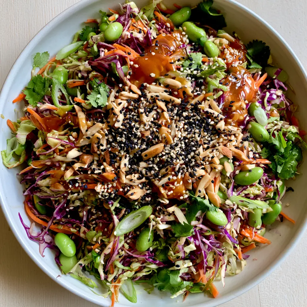 Shallow white bowl filled with Crunchy Asian Cabbage Salad, topped with toasted slivered almonds and cilantro.