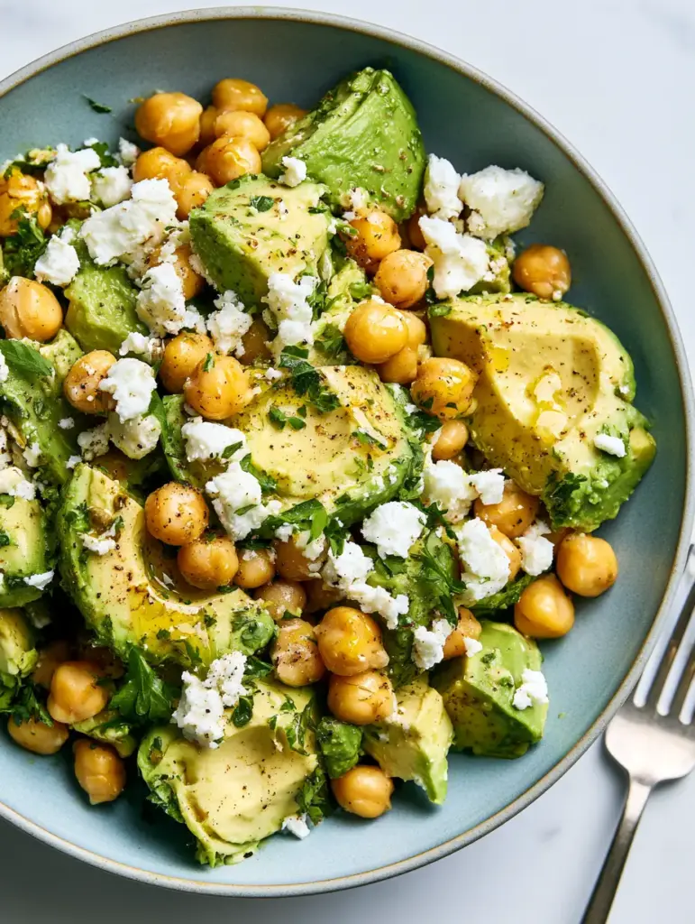 Step-by-step assembly of a chickpea feta avocado salad with red onion half-moons and diced English cucumbers.