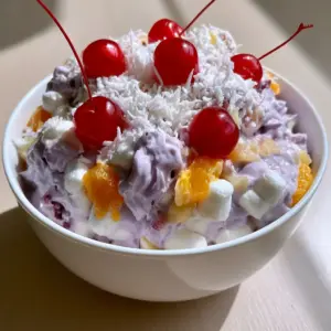 A close up smartphone photo of Better Than Sex Fruit Salad featuring purple cream and shredded coconut. (Better Than Sex Fruit Salad)