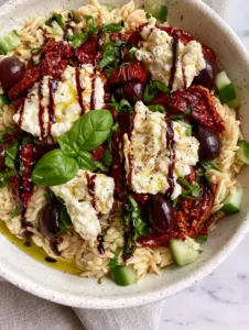 Close up of al dente orzo pearls glistening with olive oil and topped with basil. (balsamic orzo salad)
