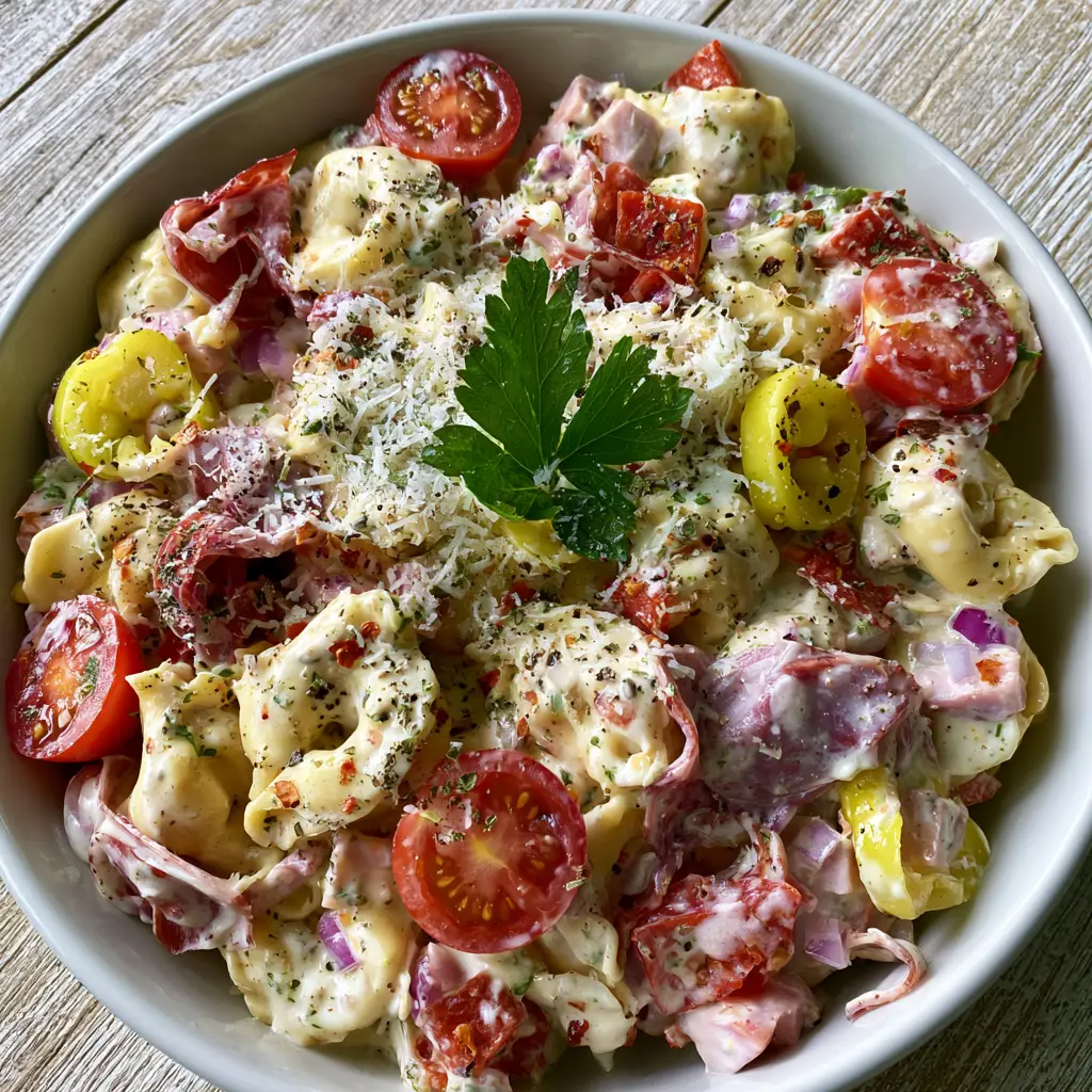 Wide angle view of Italian Grinder Tortellini Salad on a rustic wooden table with bright natural light.