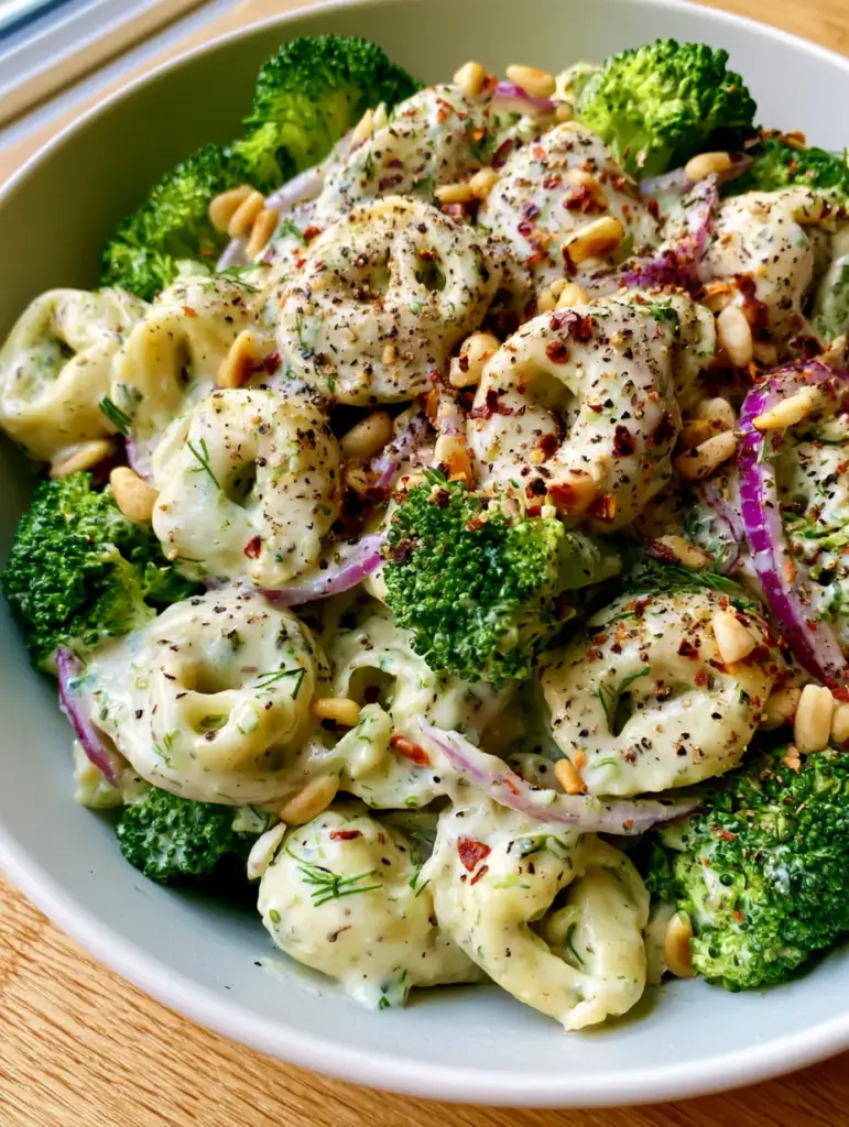 Detailed shot of Tortellini Broccoli Salad featuring bright green blanched broccoli and coarse cracked black pepper.