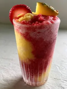 Close up of pineapple strawberry slushies with a dense soft-serve consistency and fresh fruit garnish.