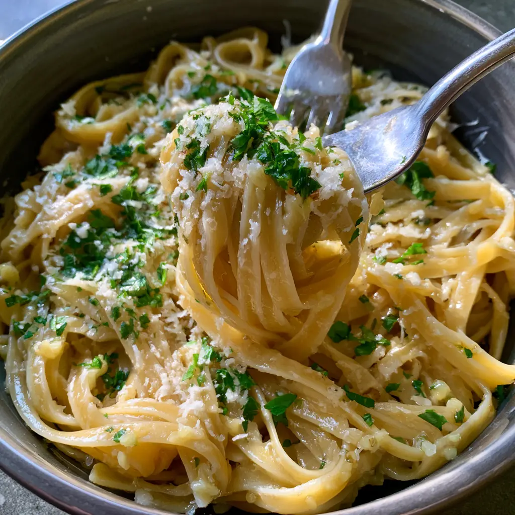 Top down view of Garlic Butter Pasta showing the softened minced garlic and fresh herbs.
