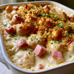 Close up of bite-sized chicken and ham cubes in a thick Swiss cheese sauce for Chicken Cordon Bleu Casserole.