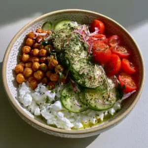 Detailed view of white cottage cheese curds topped with golden-brown chickpeas and fresh vegetables in a Cottage Cheese Chickpea Salad Bowl.