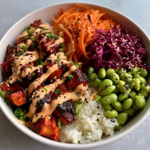 Close up of bite-sized chicken pieces with a deep reddish-brown caramelized glaze in Korean BBQ Chicken Bowls.