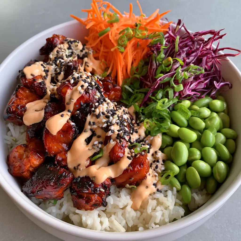 A white ceramic bowl filled with steamed rice, purple cabbage, carrots, and edamame for Korean BBQ Chicken Bowls.
