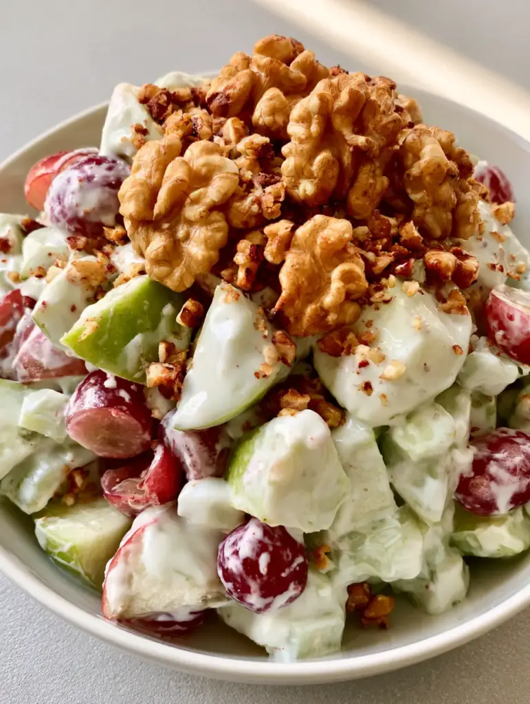 Close-up of Granny Smith apple chunks and red grapes in an Apple Salad with crushed walnuts.