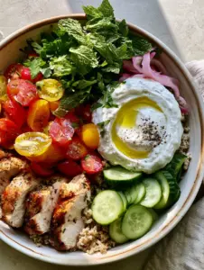 Top-down view of a ceramic bowl filled with Mediterranean ingredients for summer dinner recipes.