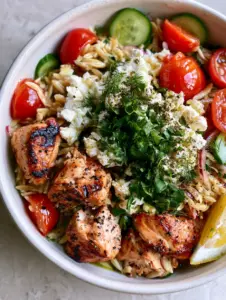 Close-up of Mediterranean Grilled Chicken Orzo Salad with glistening lemon vinaigrette and charred chicken chunks.